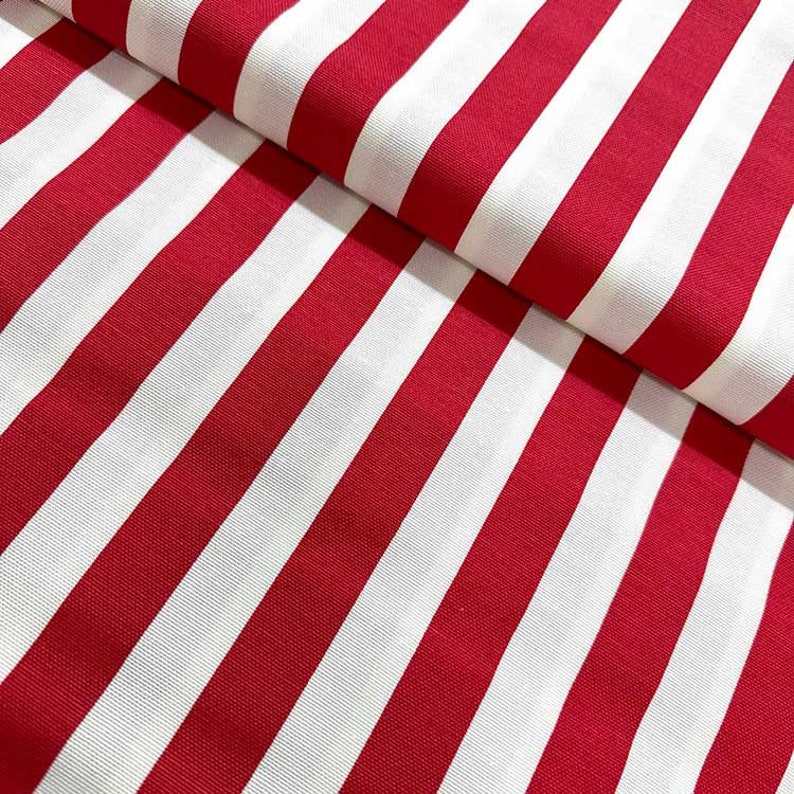 May include: Red and white striped fabric with a smooth texture. The fabric is folded in half, showing the stripes running vertically.