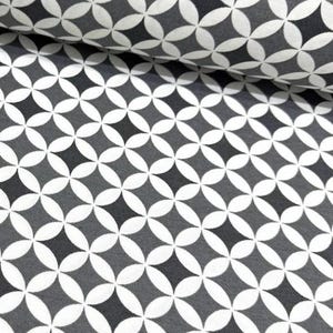 May include: A roll of fabric with a repeating geometric pattern. The design features overlapping white and gray diamond shapes on a dark gray background. The fabric is folded over, showing the pattern's continuity.