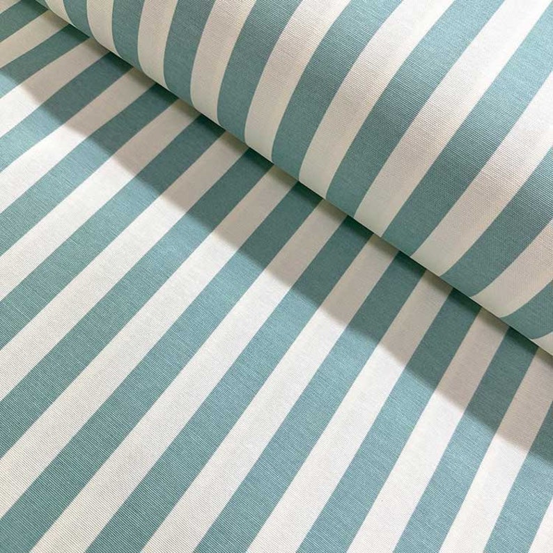 May include: A fabric with alternating white and teal blue stripes. The fabric is folded in half, showing the pattern on both sides.