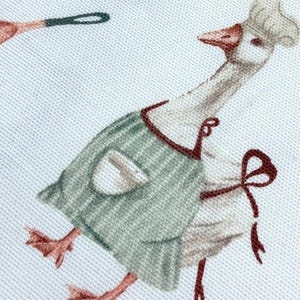 May include: A white goose wearing a green and white striped apron with a brown bow. The goose is wearing a white chef's hat and has a red beak.