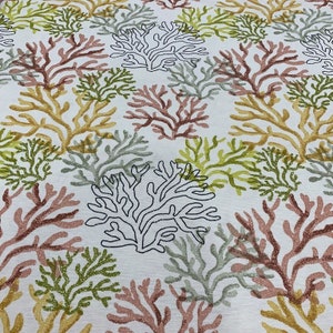 Puede incluir: Tela blanca con un patr&oacute;n repetitivo de ramas de coral en tonos de rosa, verde y amarillo.