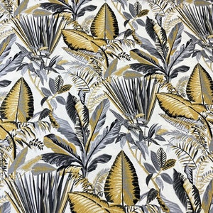 May include: Fabric featuring a repeating pattern of tropical leaves in gold, grey, and black against a white backdrop. The design includes large, detailed leaves and smaller fern-like foliage, creating a lush effect.