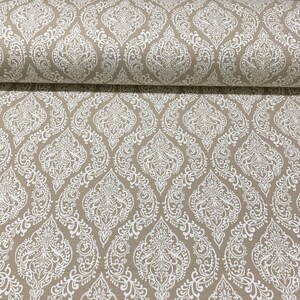 May include: Beige fabric with a white damask pattern. The pattern features intricate floral designs and swirls.