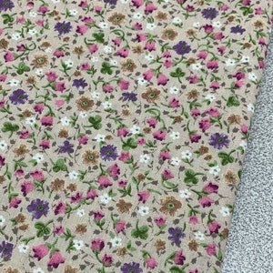 May include: Beige fabric with a small-scale floral print featuring pink, purple, and brown flowers. The fabric has a subtle texture.