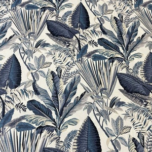 May include: Fabric featuring a botanical print with navy blue, grey, and white tropical leaves. The design showcases large, detailed leaves and smaller foliage, creating a lush, botanical pattern. The fabric has a natural, textured appearance.