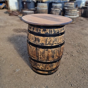 Op de afbeelding: Een houten vaten tafel met een zwarte metalen band rond de boven- en onderkant. De tafel is gemaakt van gerecycled hout en heeft een rustieke uitstraling.