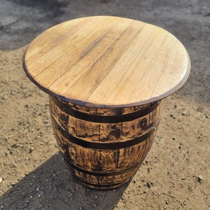 Op de afbeelding: Een houten vaten tafel met een naturel houten blad en zwarte metalen banden. De tafel is gemaakt van gerecycled hout en heeft een rustieke uitstraling.
