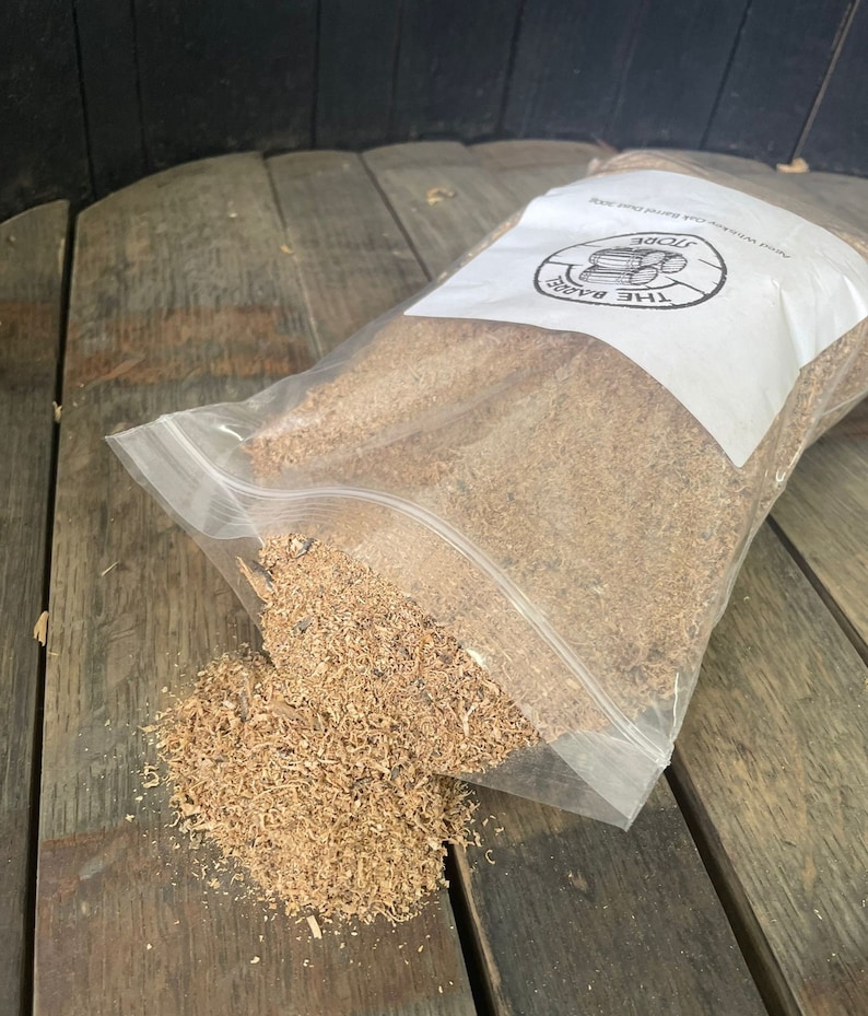 Puede incluir: Una bolsa de pl&aacute;stico transparente llena de virutas de madera de color marr&oacute;n claro. La bolsa est&aacute; etiquetada con "The Barrels Store, Add Whiskey, Oak, Bourbon, Wine"