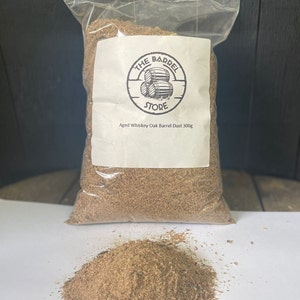 Puede incluir: Una bolsa de pl&aacute;stico transparente llena de virutas de madera marr&oacute;n. La bolsa tiene una etiqueta blanca con el texto "The Barrel Store" y "Aged Whiskey Oak Barrel Dust 300g".