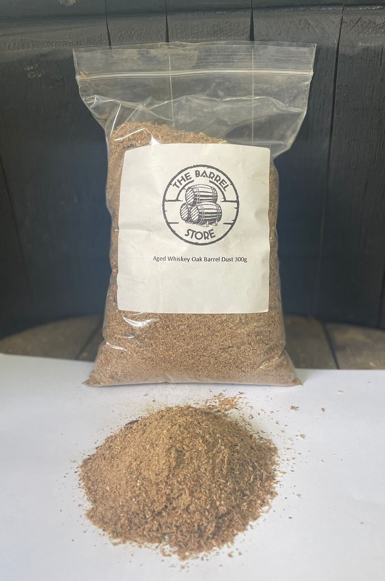 Puede incluir: Una bolsa de pl&aacute;stico transparente llena de virutas de madera marr&oacute;n. La bolsa tiene una etiqueta blanca con el texto "The Barrel Store" y "Aged Whiskey Oak Barrel Dust 300g".