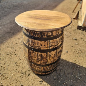 Op de afbeelding: Een houten vaten tafel met een naturel houten blad en zwarte metalen banden. De tafel is gemaakt van een hergebruikt vat en heeft een rustieke, industri&euml;le uitstraling.