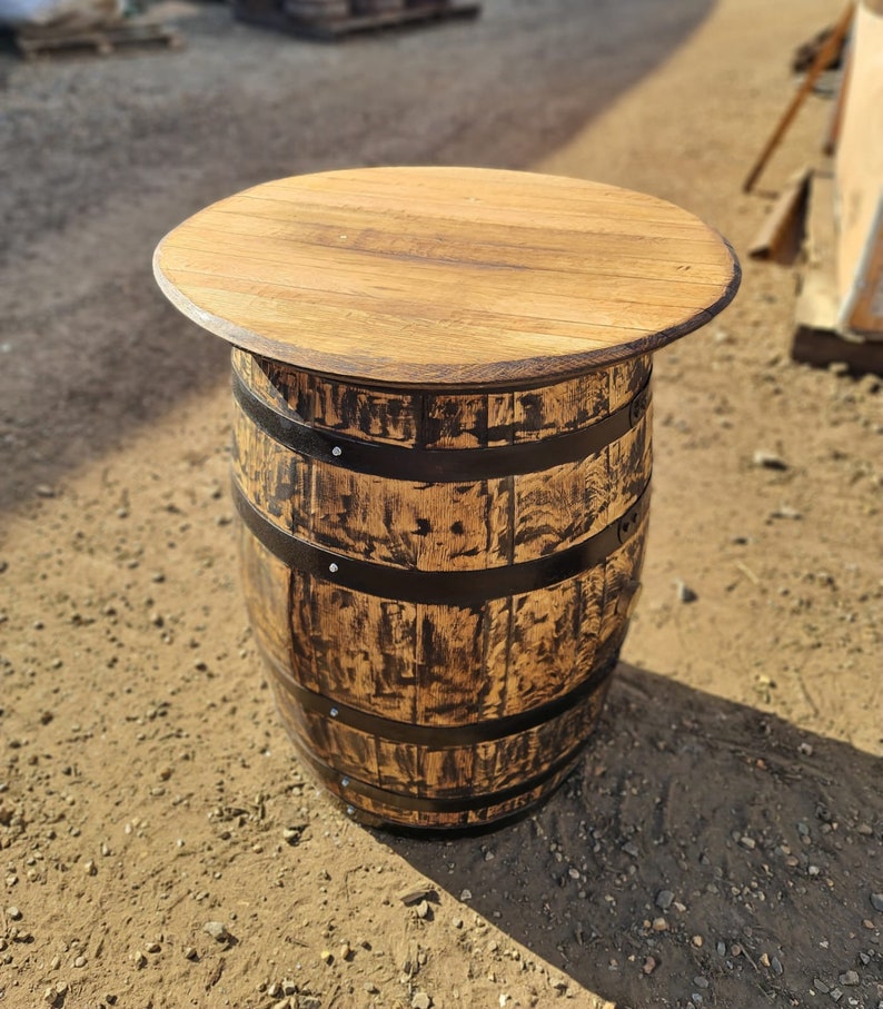 Op de afbeelding: Een houten vaten tafel met een naturel houten blad en zwarte metalen banden. De tafel is gemaakt van een hergebruikt vat en heeft een rustieke, industri&euml;le uitstraling.