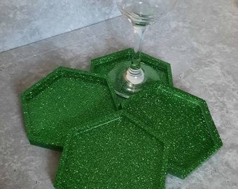 Peut inclure: Quatre sous-verres hexagonaux en paillettes vertes avec un verre à vin en verre transparent sur le dessus.