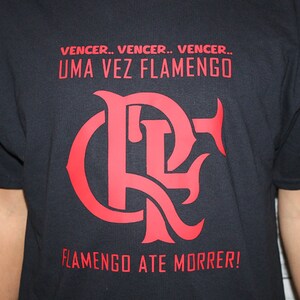 Puede incluir: Camiseta negra con un logotipo rojo de Flamengo y el texto "Vencer... Vencer... Vencer... Uma Vez Flamengo" y "Flamengo Ate Morrer!"
