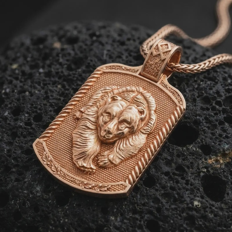 Rose gold plated bear and cub necklace displayed on textured volcanic stone, showcasing the detailed bear portraits, close parent-child composition, rope-style border, and wildlife pendant design.