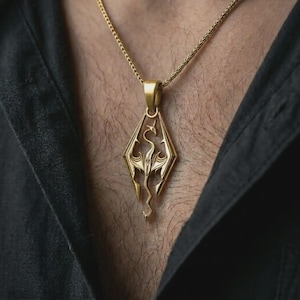 Gold plated Skyrim dragon pendant necklace worn on the chest, premium lifestyle jewelry photo with the fantasy dragon pendant centered on a spiga chain.
