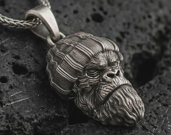 May include: A silver pendant necklace with a detailed gorilla head. The pendant is intricately carved with textured fur and facial features, suspended from a silver chain. The gorilla pendant is a striking piece of jewellery.