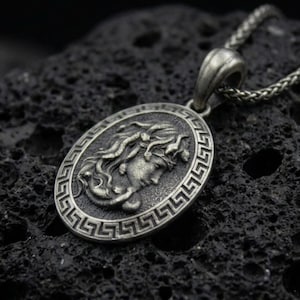 Oxidized 925 sterling silver Medusa coin pendant on volcanic rock, Greek key border medallion with raised goddess profile relief