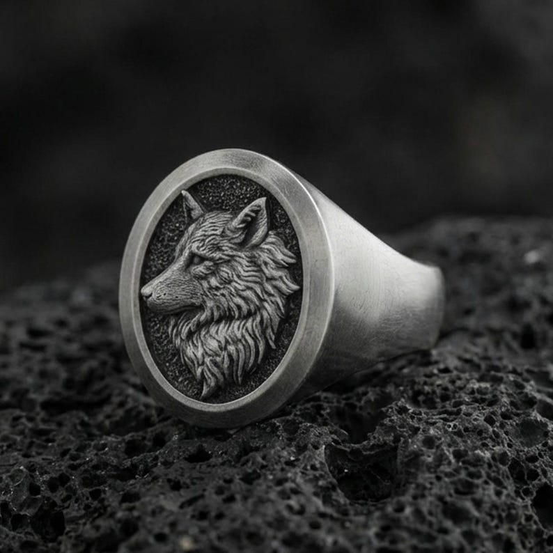 Oxidized sterling silver wolf signet ring on volcanic rock, macro closeup with deep shadow contrast
