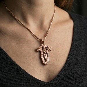 Rose gold plated gothic cross pendant necklace worn on the neck, lifestyle wear shot with elegant rosy shine and clear gothic cross detailing.