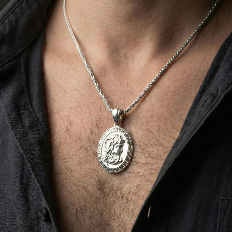Polished silver Medusa coin necklace worn on neck, Greek key framed medallion with classic Greek goddess profile detailing