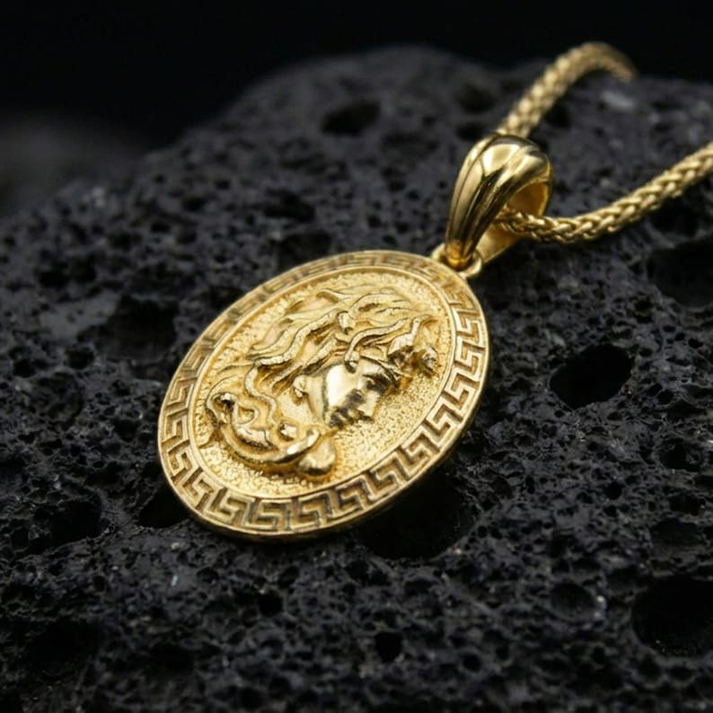 Gold plated Medusa coin pendant on volcanic rock, Greek key border medallion with classical Greek mythology face relief