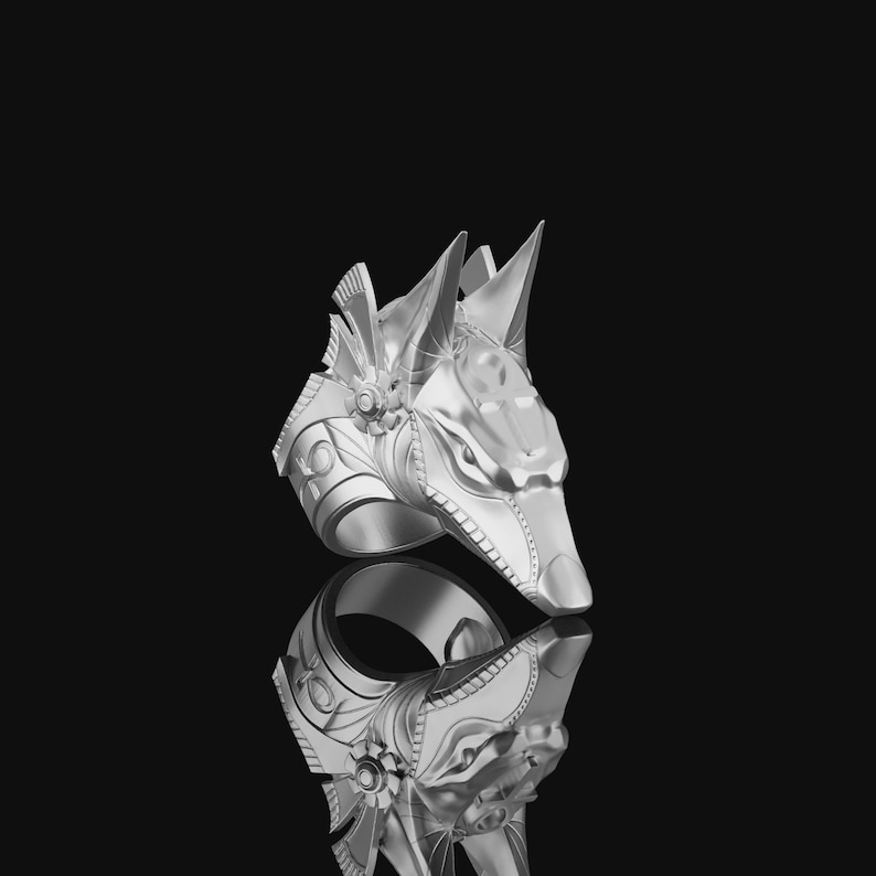 May include: Silver ring with an Anubis head design. The ring is detailed with intricate carvings and a textured finish.