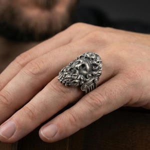 Oxidized sterling silver Zeus ring worn on finger, bold Greek god design with detailed beard and curls, masculine lifestyle hand shot