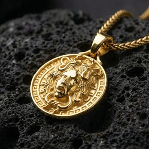 Gold plated Medusa pendant necklace showcased on volcanic rock as a symbol of power, protection, and transformation
