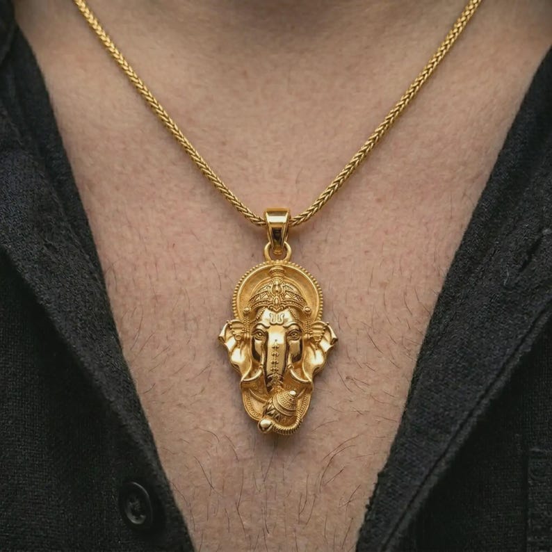 Gold plated Ganesha pendant necklace worn on the chest, premium lifestyle jewelry photo with the Ganesha pendant centered on a spiga chain.