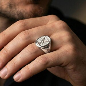 Polished silver Lucifer sigil ring on the finger, macro lifestyle image emphasizing the sharp relief lines and smooth signet profile