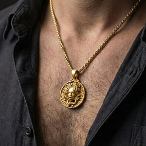 Gold plated Medusa pendant necklace worn by man as bold mythology statement jewelry