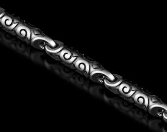 May include: Close-up of a silver chain with an ornate, repeating pattern. The chain links are connected and feature a swirling, scroll-like design. The background is black, highlighting the chain's details.