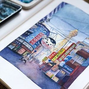 May include: Watercolour painting of a street scene in Japan. The painting features a blue and white pufferfish sign, a tall building, and a street lined with shops and people. The painting is done in a realistic style and captures the vibrant energy of a Japanese city.