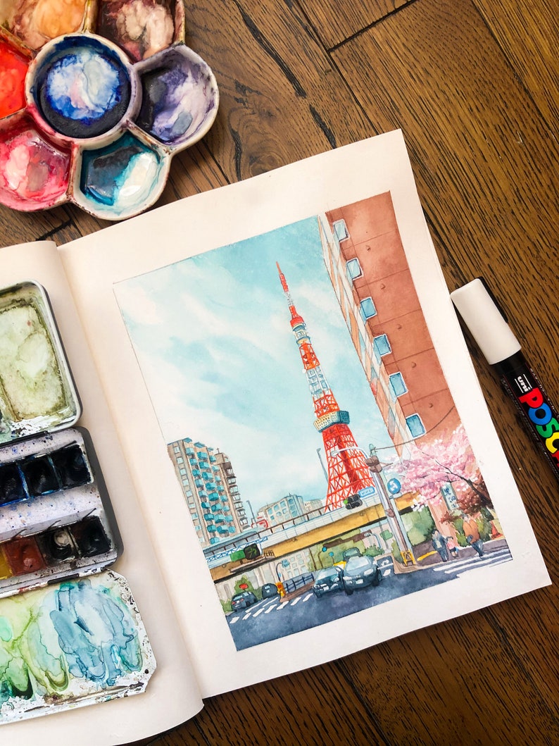 May include: Watercolour painting of a cityscape with a red and white tower in the background. The tower is surrounded by buildings and a street with cars. There are pink cherry blossoms in the foreground.