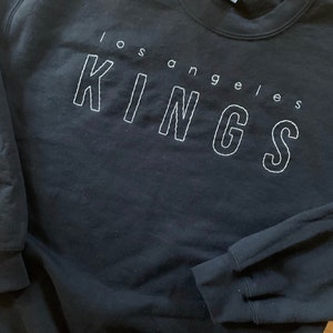 May include: Black sweatshirt with white embroidered text that reads "Los Angeles Kings".