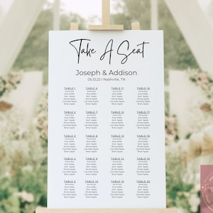 Puede incluir: Un plano de asientos blanco sobre un caballete con el texto "Take A Seat" en escritura elegante. El gráfico enumera los nombres de los invitados por número de mesa para la boda de Joseph & Addison en Nashville, TN, el 13 de mayo de 2022. El diseño incluye un logotipo floral.