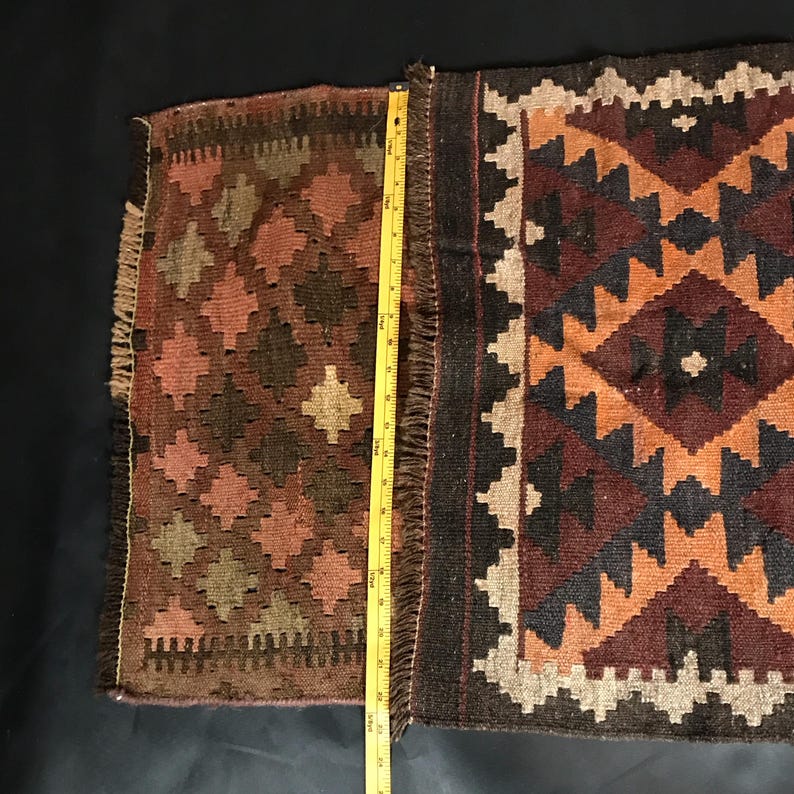 May include: A brown, black, and orange patterned rug with fringe on all sides. The rug is approximately 30 inches long.