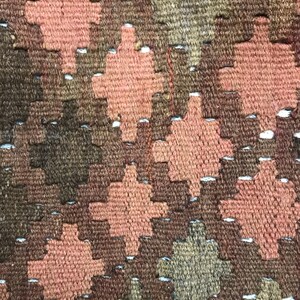 May include: Close-up of a woven fabric with a geometric pattern in shades of brown, pink, and white.