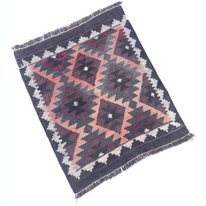May include: A traditional rug with a geometric pattern in shades of brown, red, and cream. The rug has a fringed border.