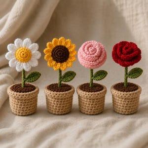Könnte beinhalten: Vier gehäkelte Blumen in beigen Töpfen, darunter ein weißes Gänseblümchen mit gelber Mitte, eine gelbe Sonnenblume mit brauner Mitte, eine rosa Rose und eine rote Rose. Jede Blume hat einen grünen Stiel und ein einzelnes grünes Blatt.