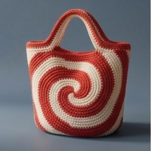Könnte beinhalten: Handgefertigte Häkeltasche mit Spiralmuster. Die Tasche hat abwechselnde Streifen aus roter und cremefarbener Wolle, die ein auffälliges Muster bilden. Sie hat einen stabilen Griff zum Tragen und ist für verschiedene Zwecke geeignet.