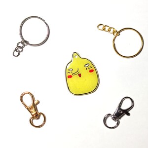 May include: Five different keychains, including a gold keychain with a yellow cartoon face, a silver keychain with a round ring, a gold keychain with a round ring, a gold swivel clasp keychain, and a silver swivel clasp keychain.