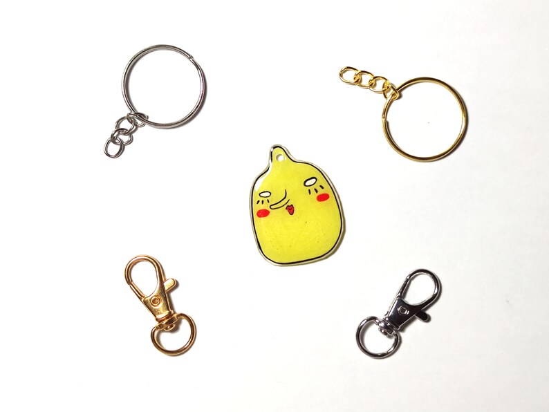 May include: Five different keychains, including a gold keychain with a yellow cartoon face, a silver keychain with a round ring, a gold keychain with a round ring, a gold swivel clasp keychain, and a silver swivel clasp keychain.