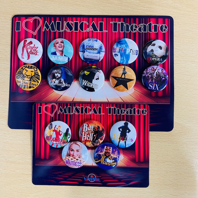 May include: Two sets of musical theatre themed button badges. The top set features badges for Kinky Boots, Jamie, Dear Evan Hansen, Hairspray, Phantom of the Opera, The Lion King, Les Miserables, Wicked, Hamilton, and Six. The bottom set features badges for Heather's, Bat Out of Hell, Matilda, Waitress, and Aladdin.