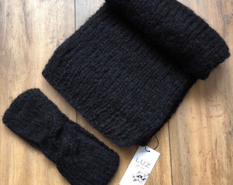 Può includere: Un set di sciarpa e fascia per capelli neri lavorati a maglia. La sciarpa è arrotolata e la fascia è piatta, entrambe realizzate con un filato spesso e strutturato. Un'etichetta bianca con il marchio "LUZ" è attaccata.