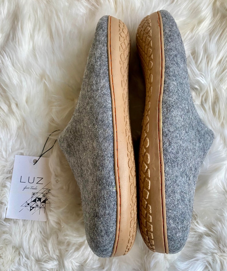 Puede incluir: Un par de zapatillas de lana grises con suelas de cuero marr&oacute;n. Las zapatillas tienen una suela texturizada y son de la marca Luz.