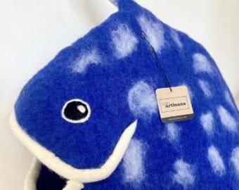 May include: A blue felted wool fish-shaped pet cave with white spots, a white mouth opening, and a dorsal fin. A small square tag attached to the side features the text "felt artisans" in black lettering on a light brown background.