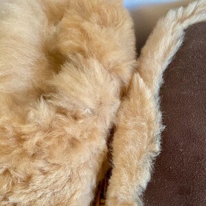Op de afbeelding: Een close-up van een bruin nep bont kussen met een zachte, pluche textuur. Het kussen is gemaakt van een pluche materiaal en heeft een warme, uitnodigende uitstraling.