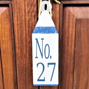 May include: A white wooden sign with blue trim and the text "No. 27" hanging on a wooden door.